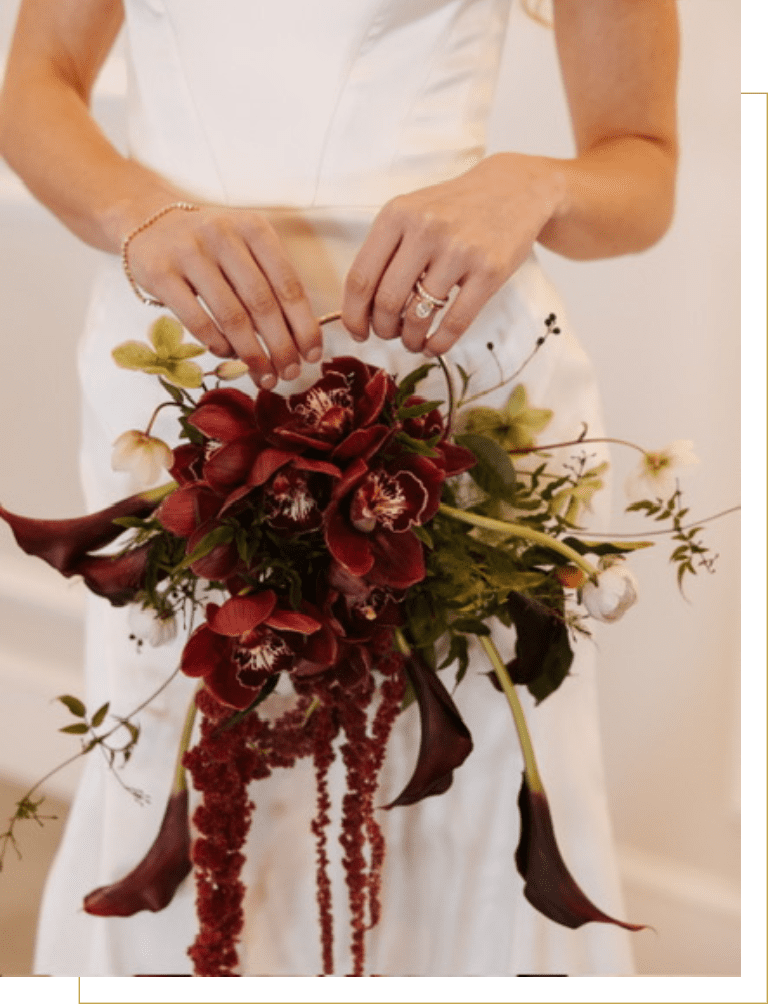 Bride holding cascading burgundy bouquet with orchids
