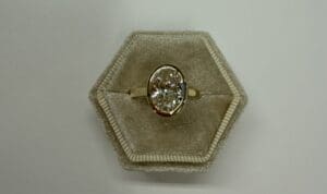Gold ring with oval diamond in box.